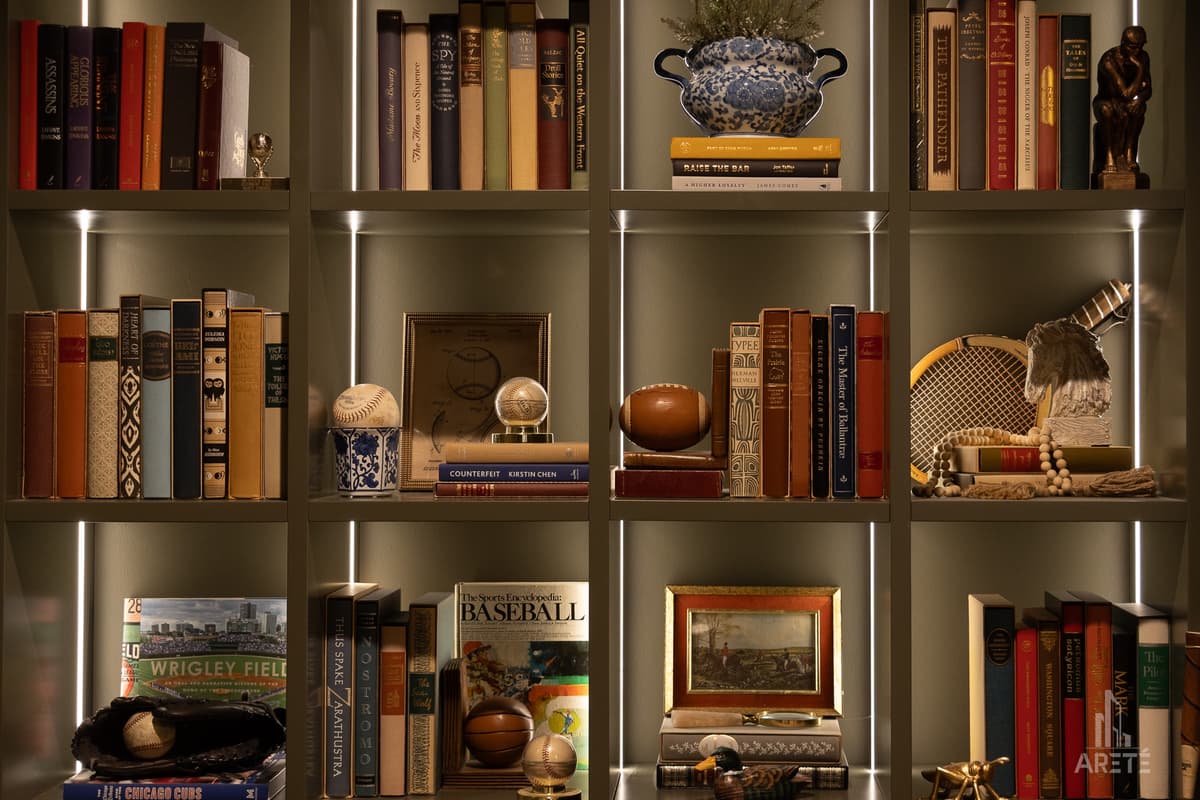 Finished basement library wall with lit built-in shelves