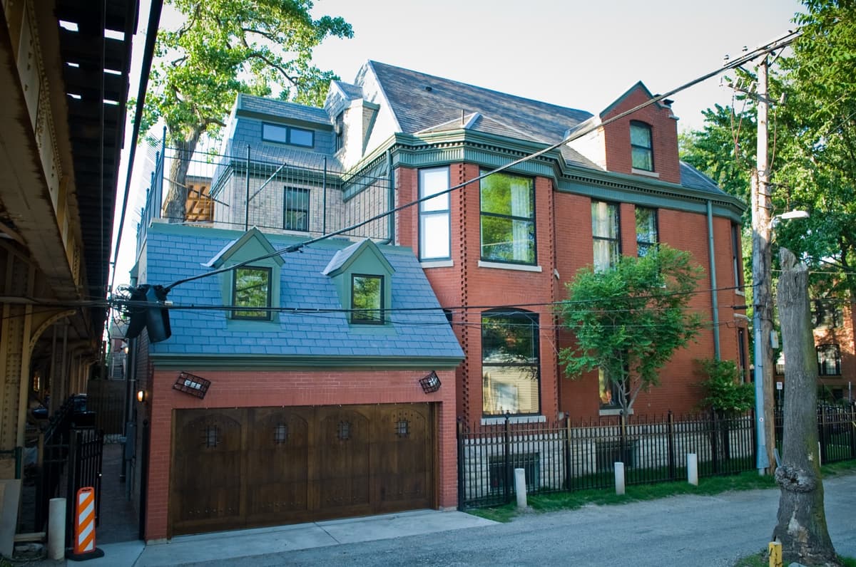 New home addition with a garage beside a brick Victorian home