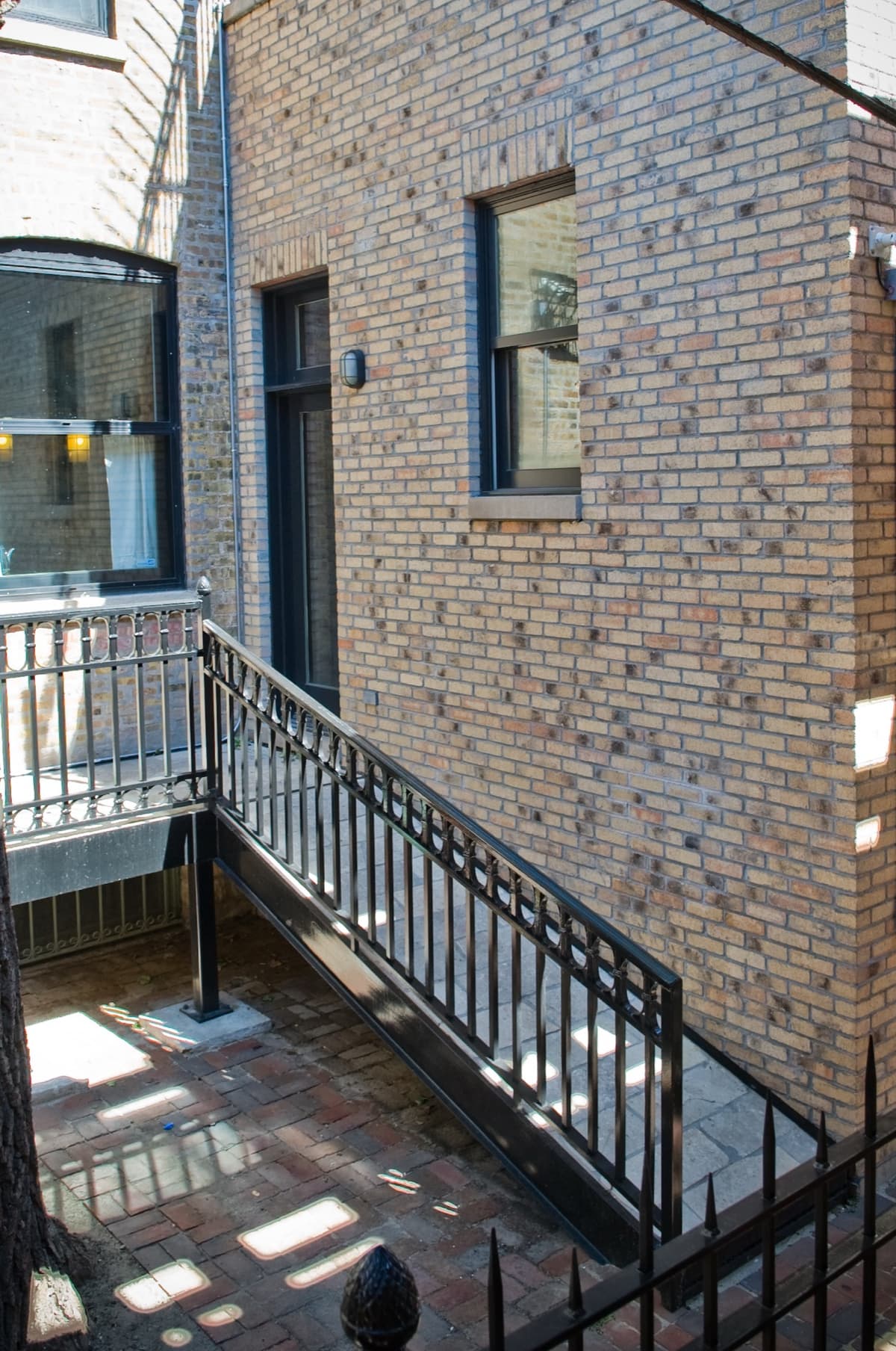 Wrought iron deck stairs and handrail beside a brick home addition