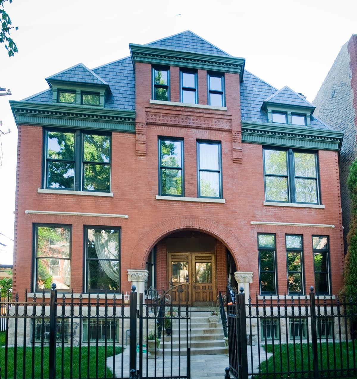 Brick Victorian home with new windows and a wrought iron fence