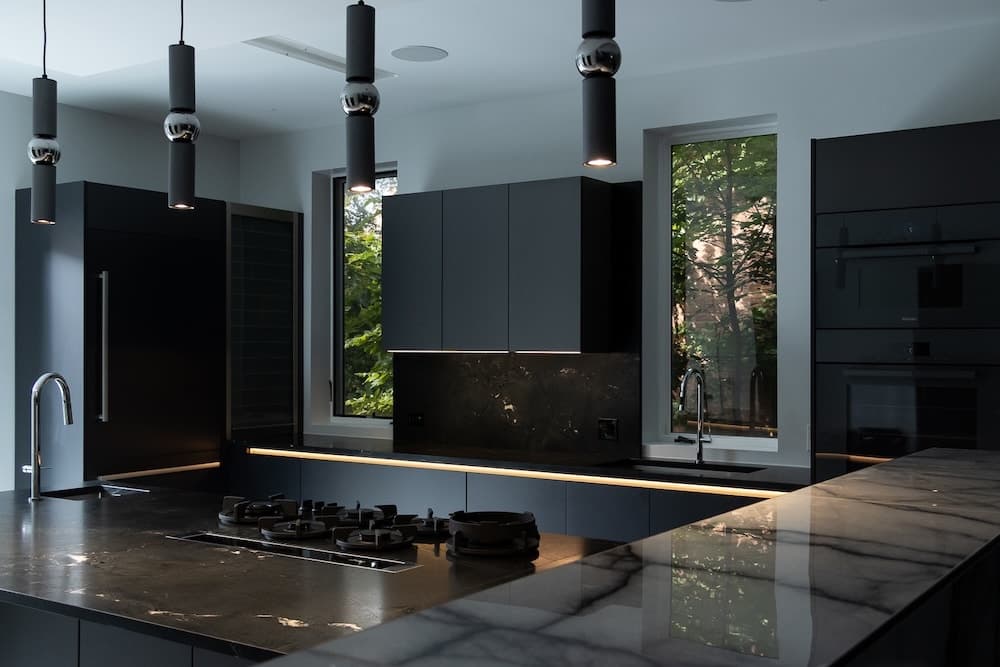 Dark kitchen with black cabinets and black pendant lights