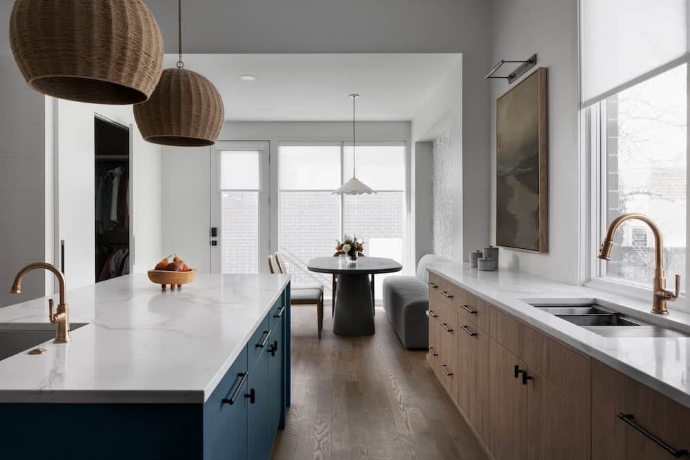Kitchen with a blue island, woven pendants and a dining nook