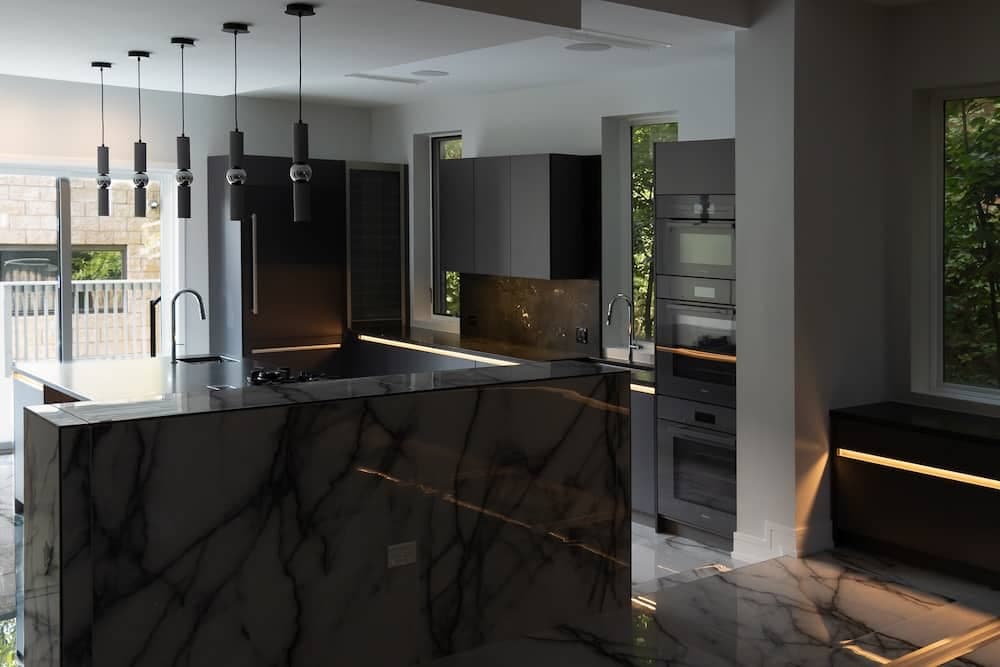 Kitchen with a black marble island and slim pendant lights