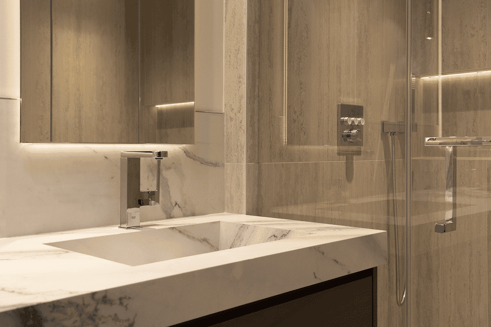 Bathroom vanity with a marble counter beside a glass shower