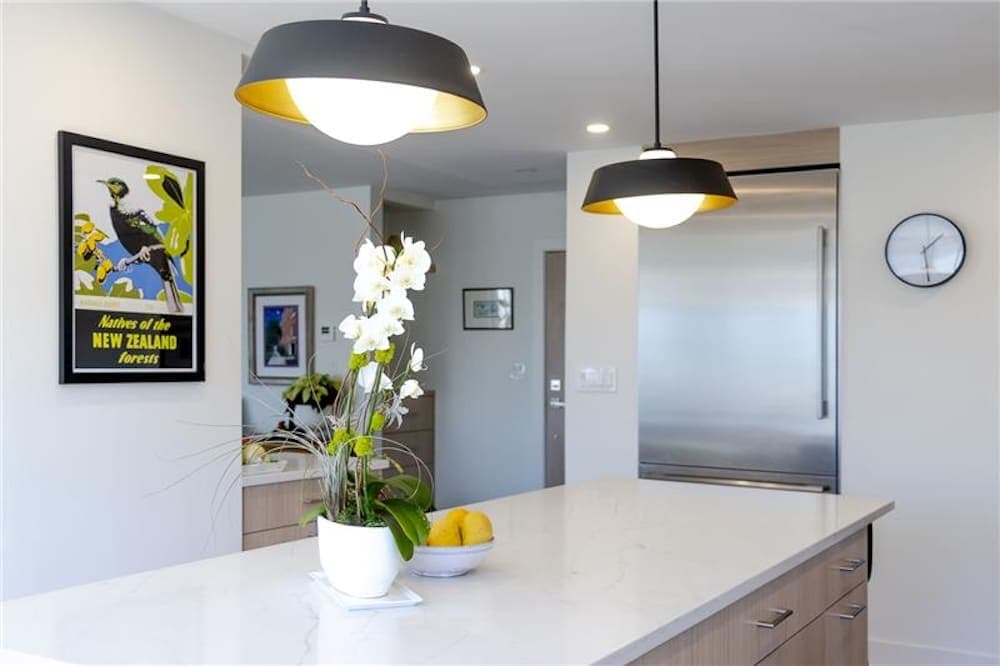 A modern kitchen with a marble island potted orchids and decorative lemons